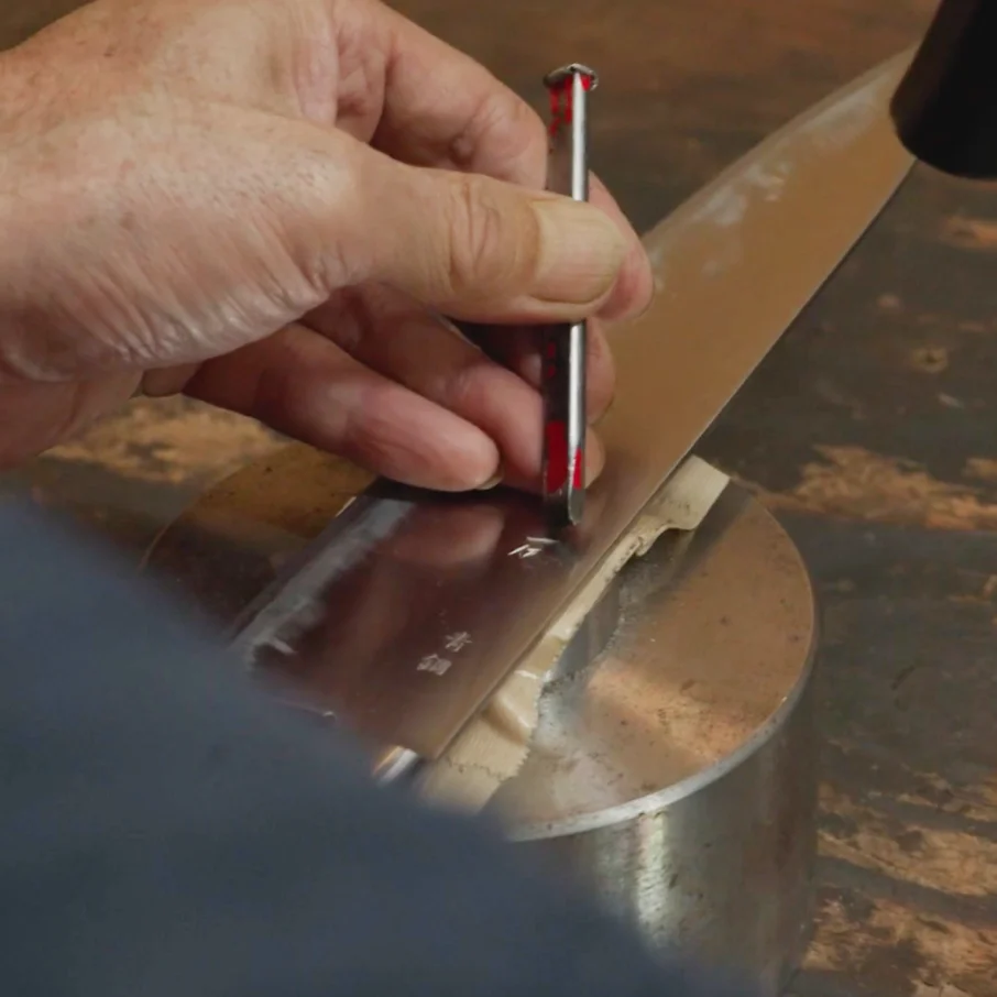 An artisan engraving a knife