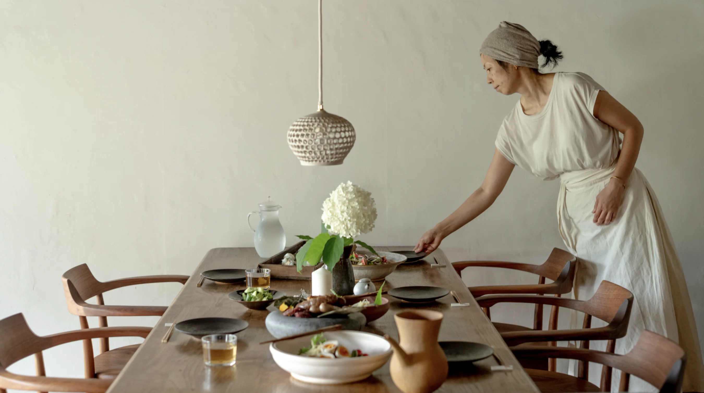 Host setting a seasonal meal at a communal dining table