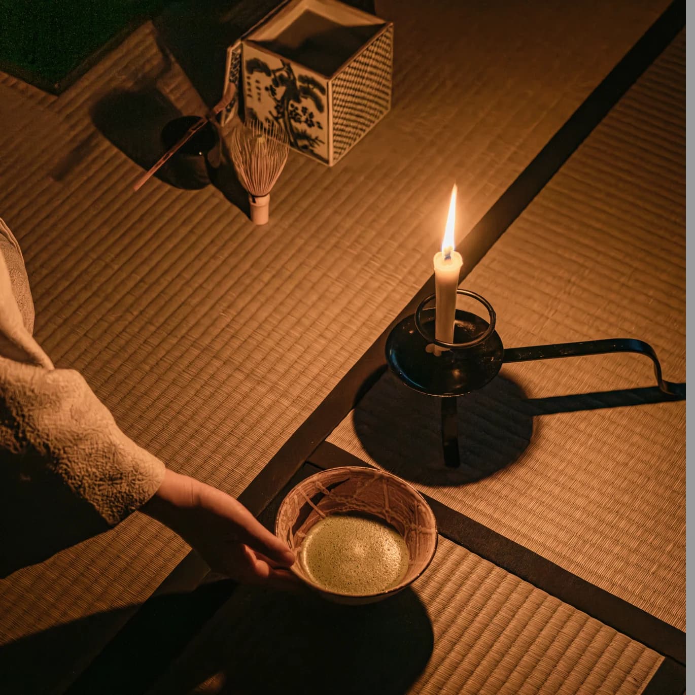 Bowl of tea on a tatami mat with candle and tea set