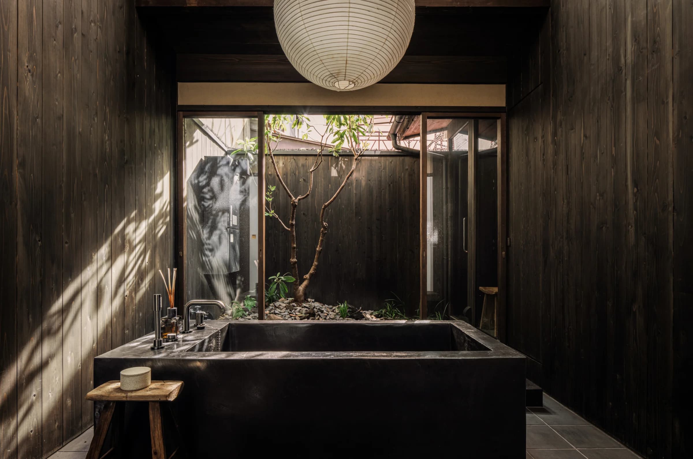 Stone soaking tub with paper lantern and view of interior garden